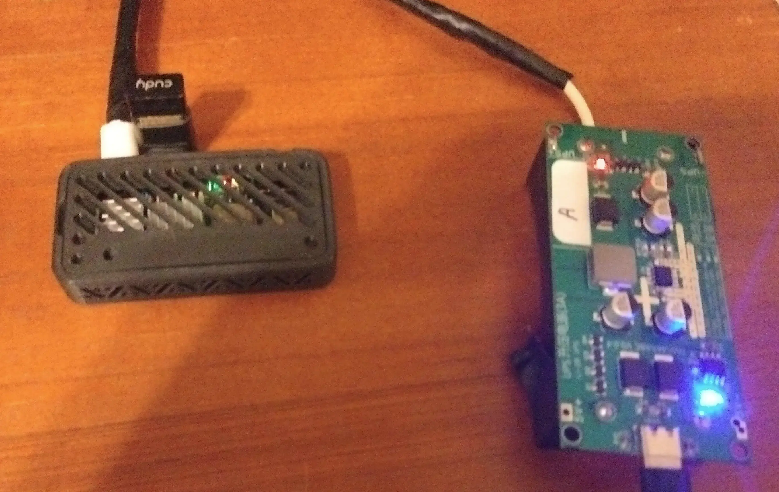 A keychain-sized server in a black, 3D printed case shown alongside a bare 5V UPS board.